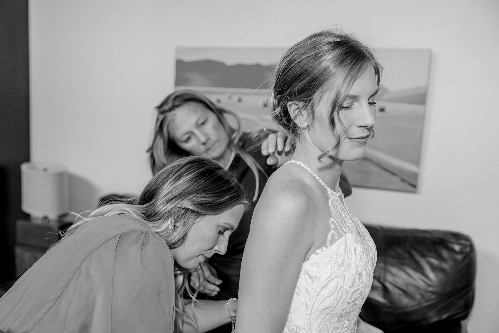 bride getting ready with sister and mom on her wedding day