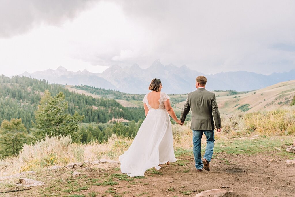 couple walks toward the teton mountains during wedding portraits