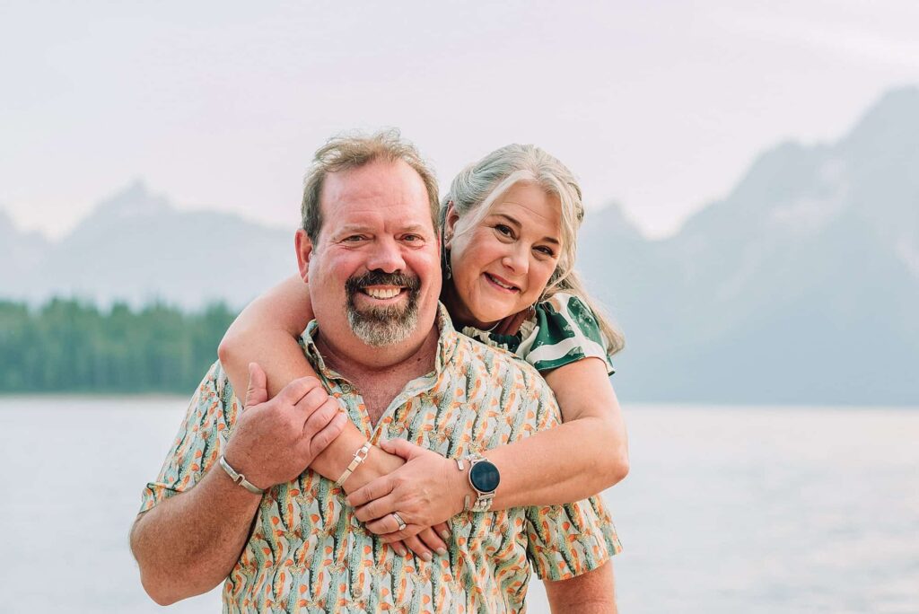 couple hugging in front of the mountains and lake