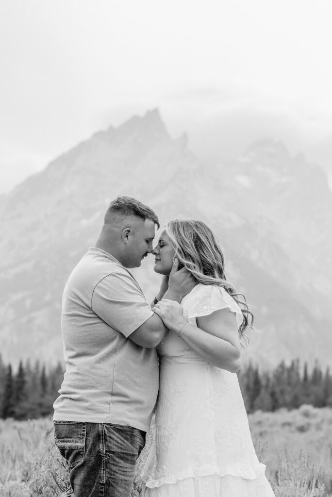 engaged couple stands in front of the Teton Mountains in romantic pose