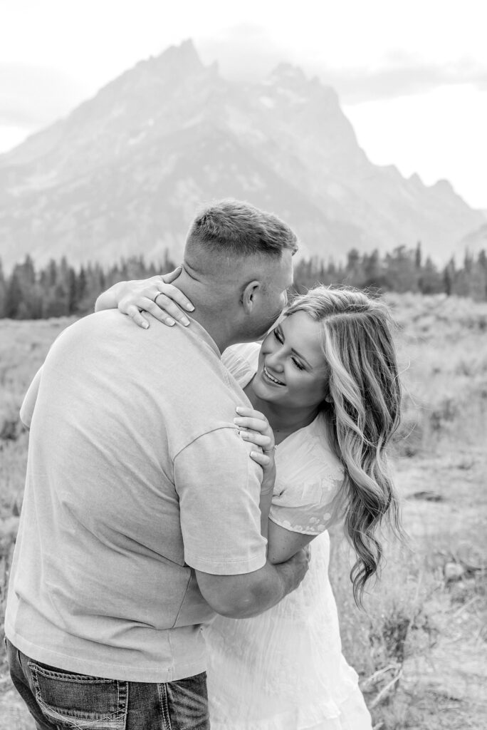 engaged couple stands in front of the Teton Mountains in romantic pose