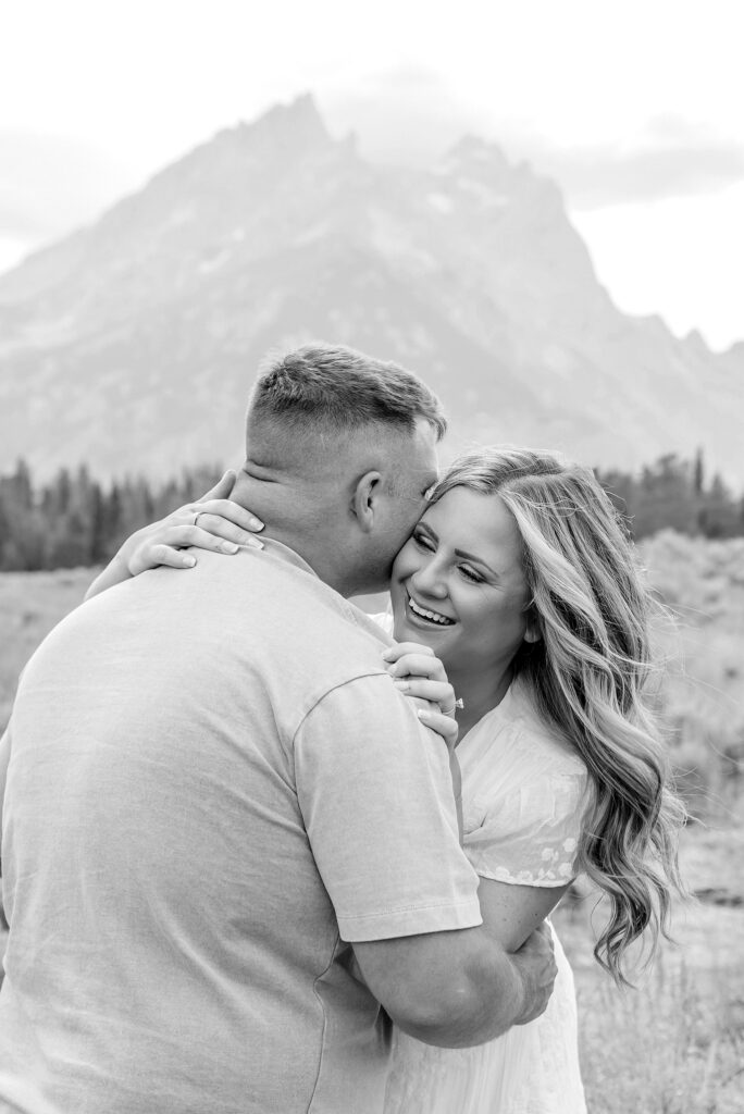 engaged couple stands in front of the Teton Mountains in romantic pose