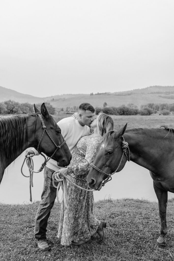 engaged Couple poses with horses at Diamond Cross Ranch