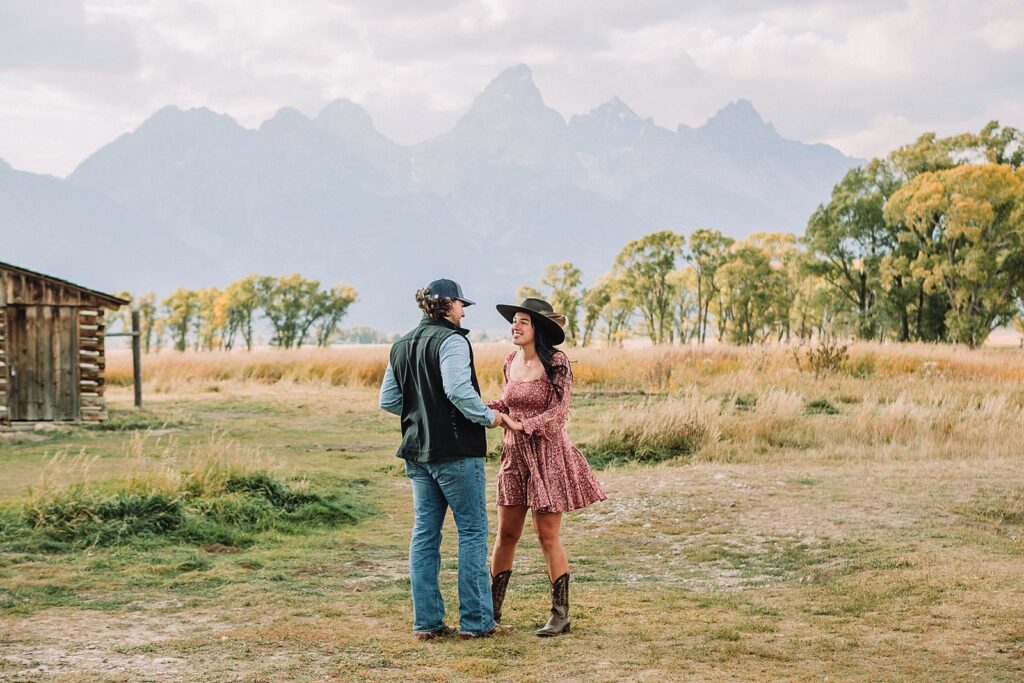 man proposes to girlfriend in fall mormon row proposal with golden grasses and the Teton Mountains