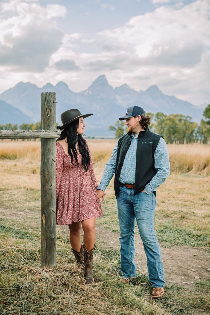 Engaged couple poses in front of the Teton Mountains and Moulton Barn