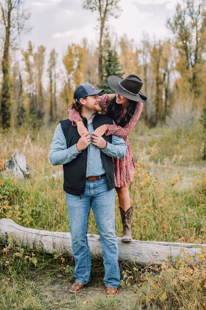 man and woman pose with hats at schwabacher landing during engagement photos