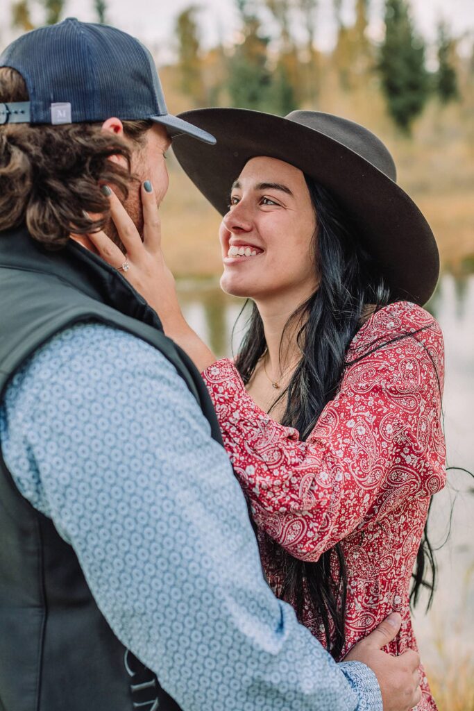 man and woman pose with hats at schwabacher landing during engagement photos