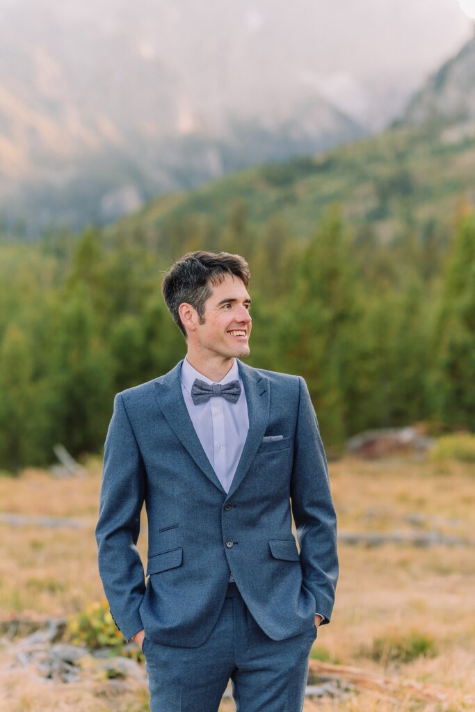 groom poses in blue wedding suit at String Lake in Jackson Hole