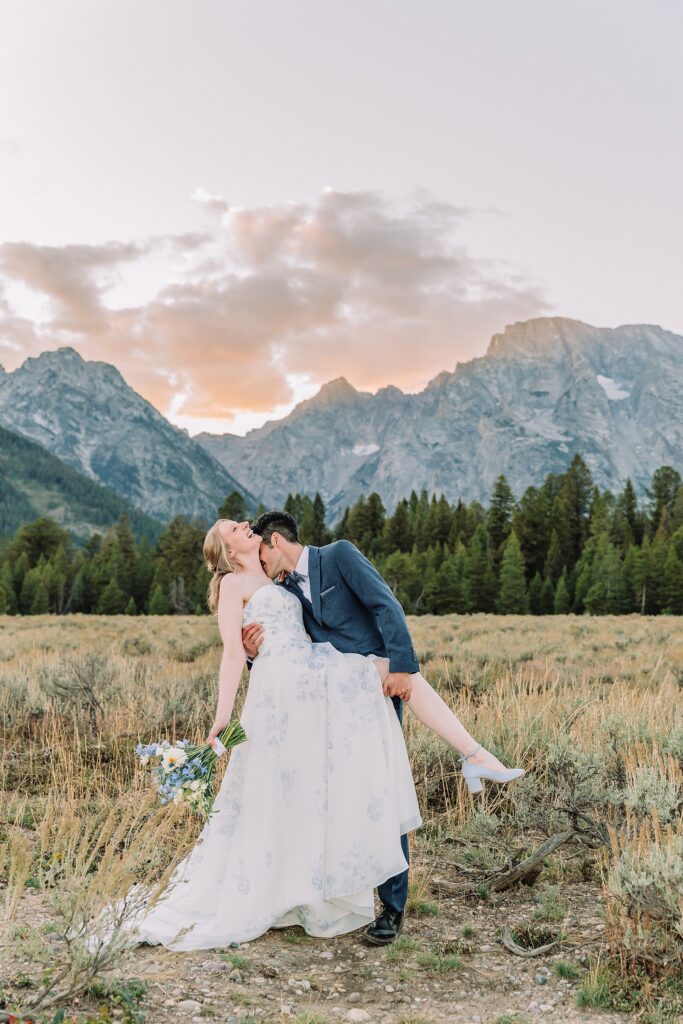 groom dips bride romantically and kisses her neck as sunset falls over the Teton moutains
