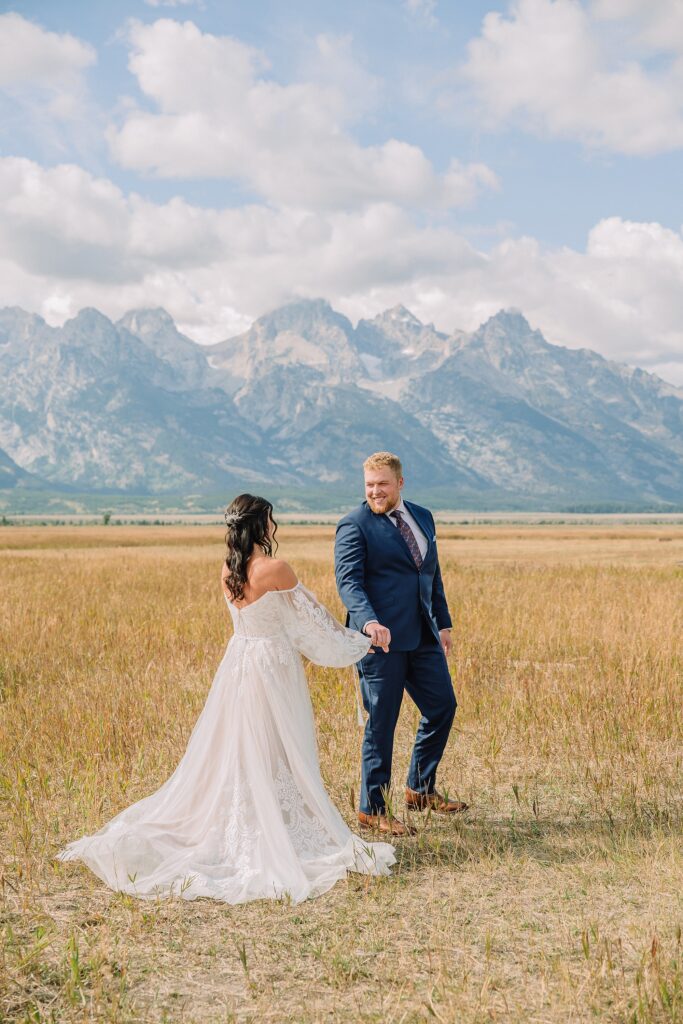 bride and groom share pre-ceremony first look in a field with mountains behind them