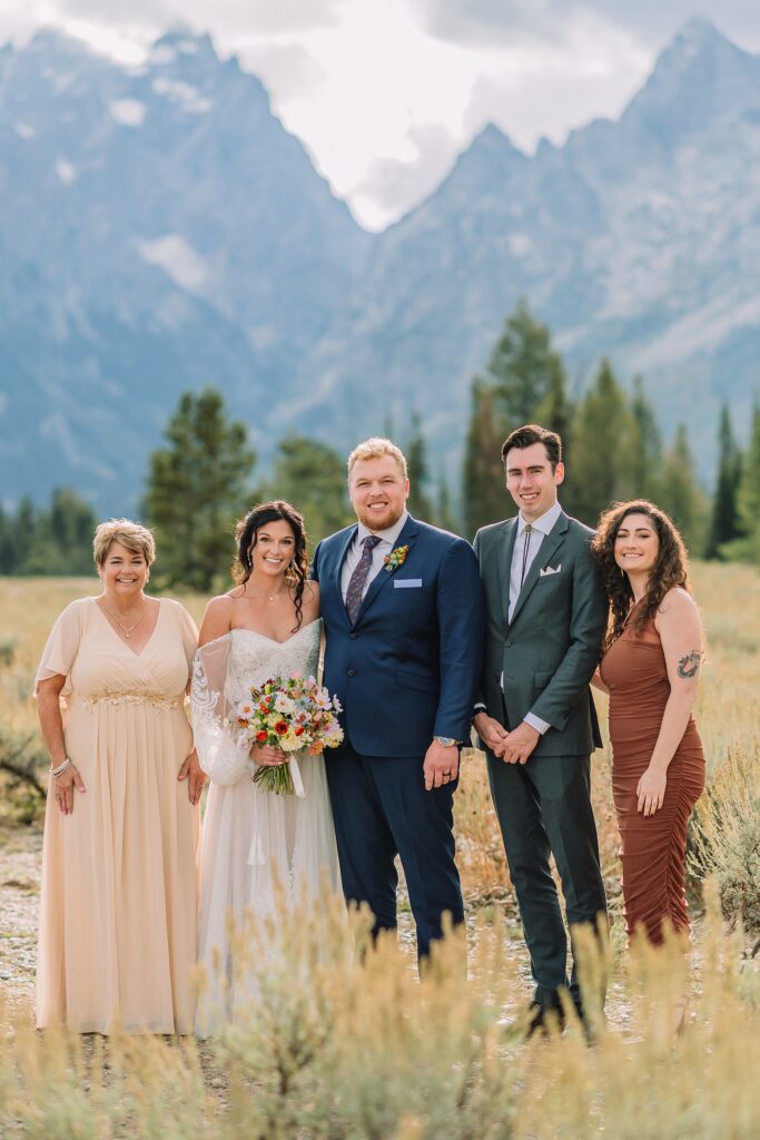 family stands in front of mountain views on wedding day