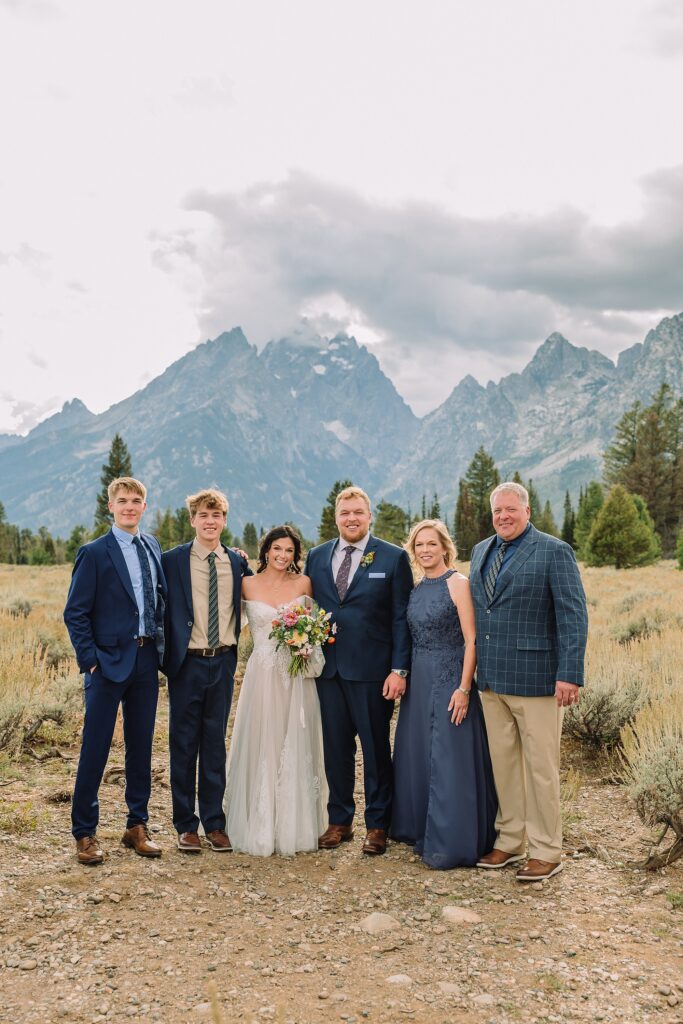 family stands in front of mountain views on wedding day