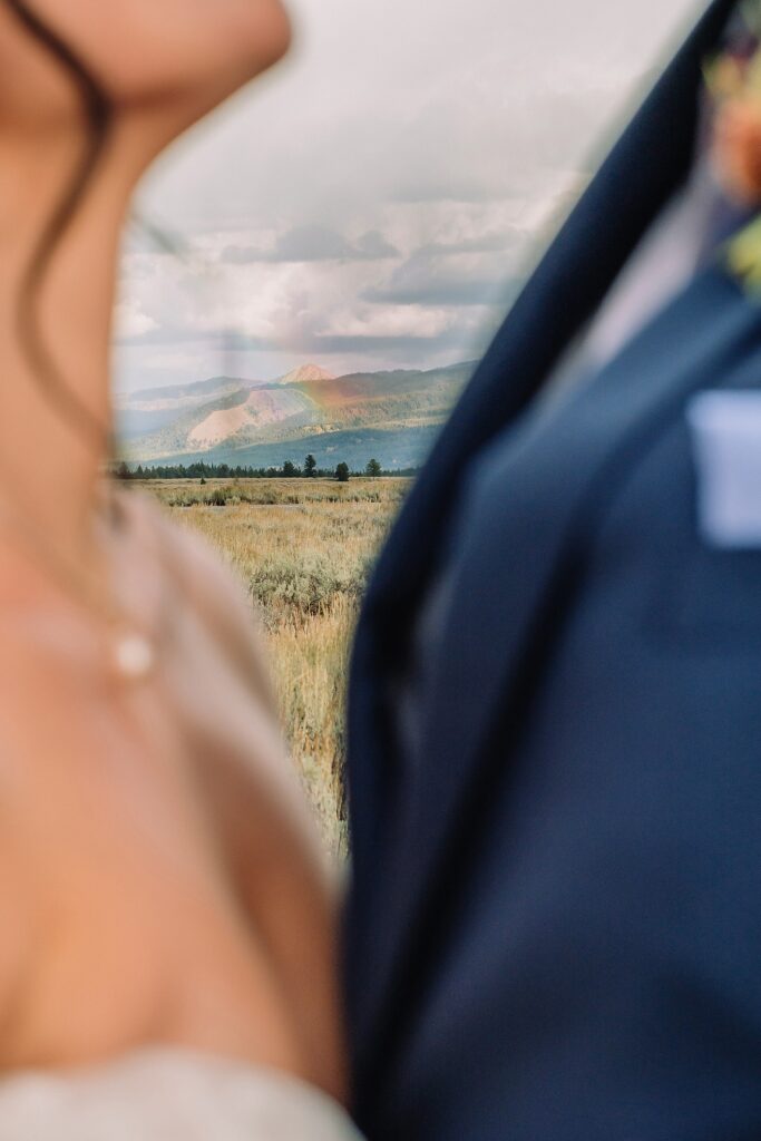 close up of bride and groom with a rainbow visible between them