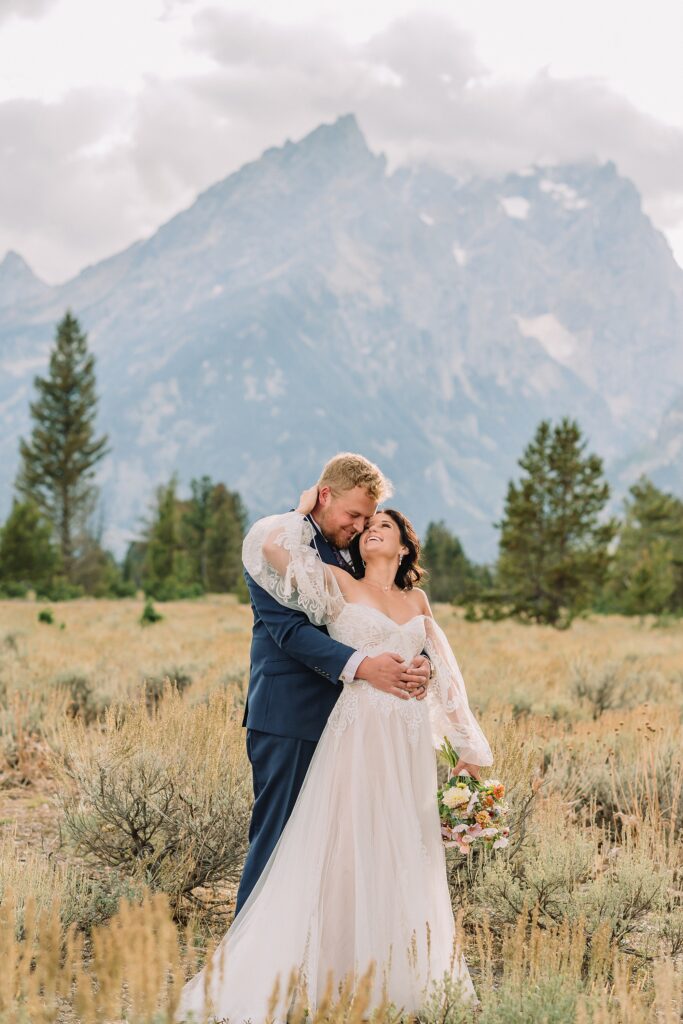 bride and groom pose romantically at mountain view turnout in wedding attire