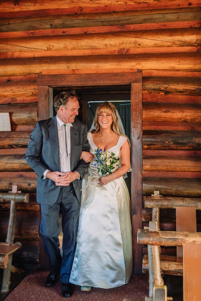 Grand Teton National Park micro wedding Chapel of the Transfiguration bride and groom portraits bride groom cowboy hat bolo tie mountain wedding Chapel of the Transfiguration bell ringing celebration Jackson Hole Wedding Photographers rustic chapel wedding log cabin ceremony