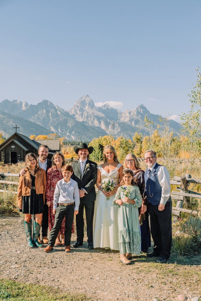 Grand Teton National Park micro wedding Chapel of the Transfiguration bride and groom portraits bride groom cowboy hat bolo tie mountain wedding Chapel of the Transfiguration bell ringing celebration Jackson Hole Wedding Photographers rustic chapel wedding log cabin ceremony