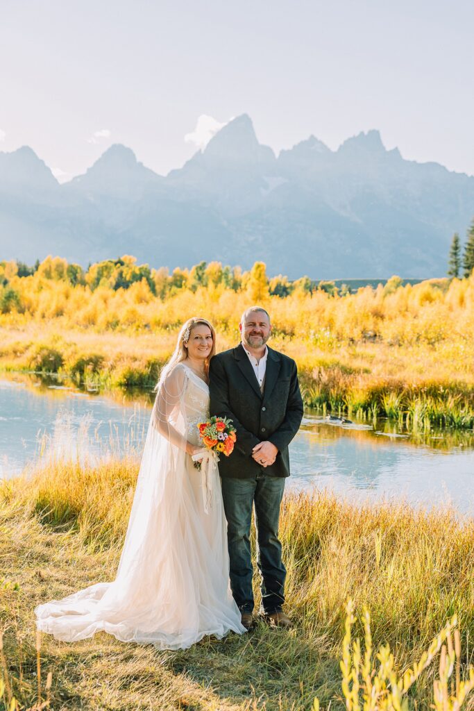Jackson Hole honeymoon wedding photos Schwabacher Landing wedding portraits Snake River wedding photography September mountain wedding photos beaded wedding dress golden hour western groom style wedding photos Teton mountain wedding portraits sheer cape wedding dress photography