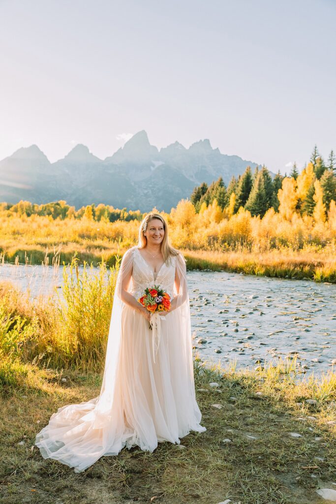 Jackson Hole honeymoon wedding photos Schwabacher Landing wedding portraits Snake River wedding photography September mountain wedding photos beaded wedding dress golden hour western groom style wedding photos Teton mountain wedding portraits sheer cape wedding dress photography