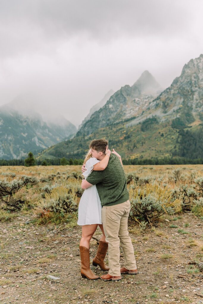 Grand Teton proposal photos at Cathedral View Turnout in the rain Cathedral View Turnout proposal photographer Jackson Hole Wyoming Genuine proposal reaction photos Grand Teton sagebrush field Moody stormy mountain proposal photography Jackson Hole jackson hole proposal photographer
