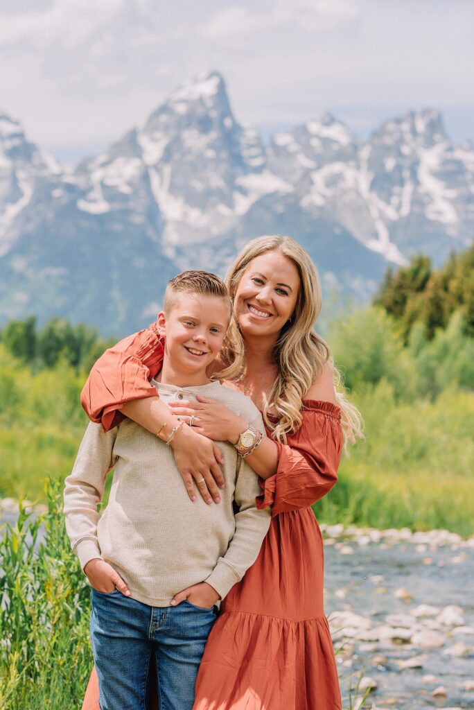 rust dress family photos with mountain backdrop boys posing naturally during Grand Teton photography session family playing in water during professional photo session Grand Teton sunrise family portraits at Schwabacher Landing cream and rust color palette mountain family photos