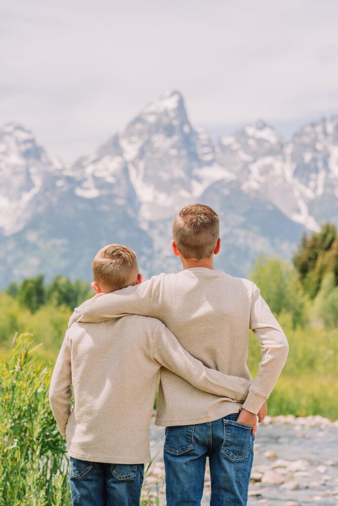 rust dress family photos with mountain backdrop boys posing naturally during Grand Teton photography session family playing in water during professional photo session Grand Teton sunrise family portraits at Schwabacher Landing cream and rust color palette mountain family photos
