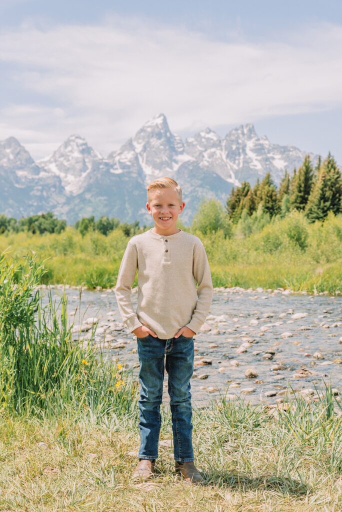 rust dress family photos with mountain backdrop boys posing naturally during Grand Teton photography session family playing in water during professional photo session Grand Teton sunrise family portraits at Schwabacher Landing cream and rust color palette mountain family photos