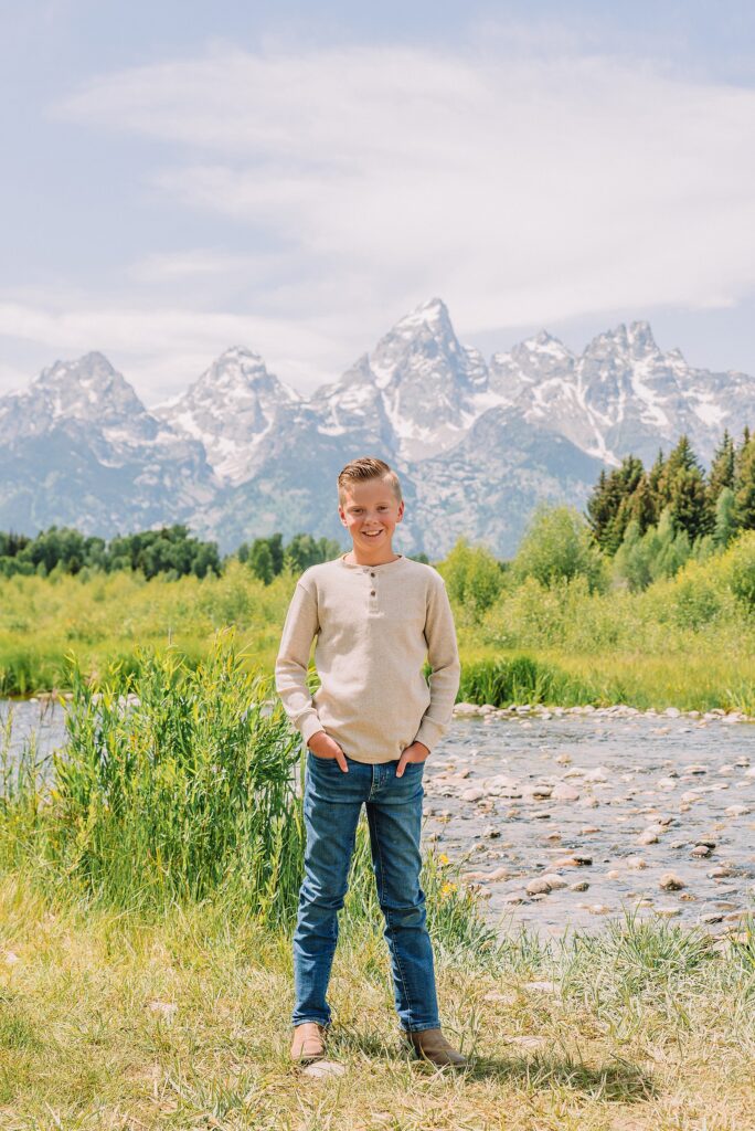 rust dress family photos with mountain backdrop boys posing naturally during Grand Teton photography session family playing in water during professional photo session Grand Teton sunrise family portraits at Schwabacher Landing cream and rust color palette mountain family photos