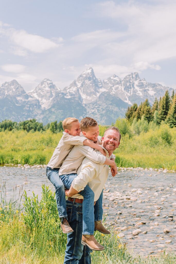rust dress family photos with mountain backdrop boys posing naturally during Grand Teton photography session family playing in water during professional photo session Grand Teton sunrise family portraits at Schwabacher Landing cream and rust color palette mountain family photos