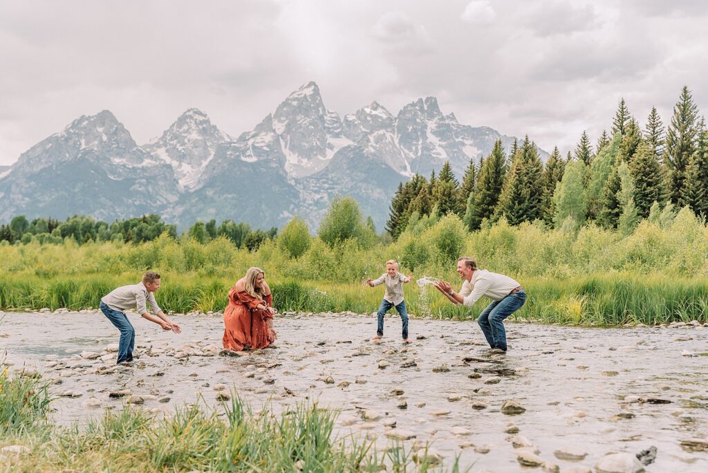 family playing in water during professional photo session Grand Teton sunrise family portraits at Schwabacher Landing cream and rust color palette mountain family photos Grand Teton vacation photographer coordinating family outfits without matching