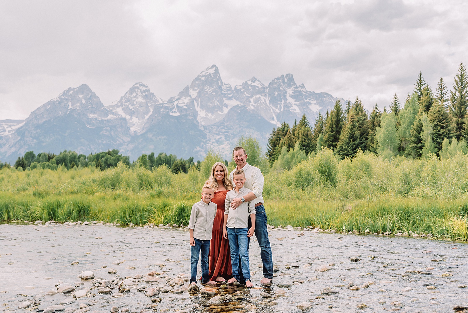 family playing in water during professional photo session Grand Teton sunrise family portraits at Schwabacher Landing cream and rust color palette mountain family photos Grand Teton vacation photographer coordinating family outfits without matching