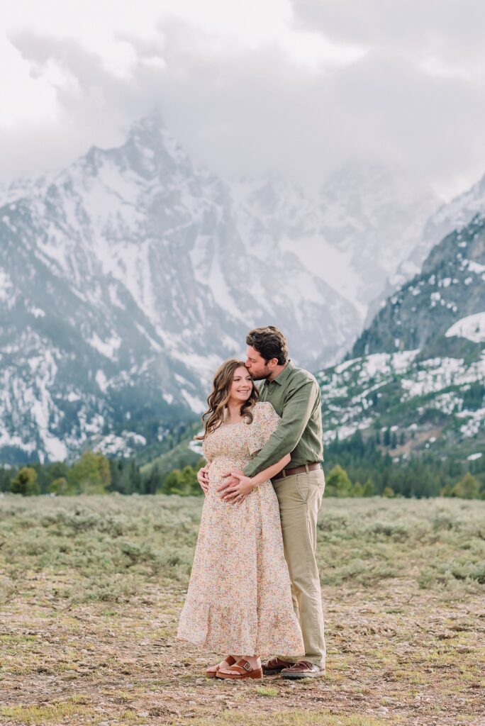 Jackson Hole babymoon maternity photos at Cathedral View Turnout Grand Teton National Park maternity session in spring Cathedral View Turnout couple photos snow capped peaks Flowery maternity dress mountain photography Jackson Hole Jackson Hole Maternity Photographer