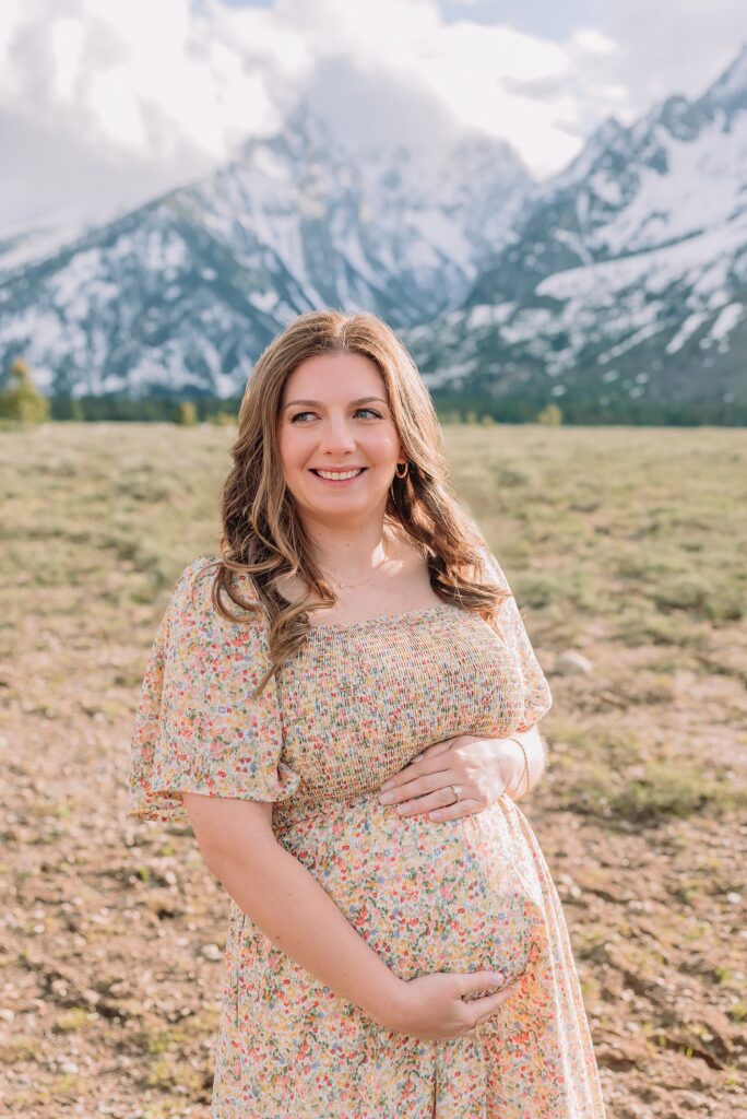 Jackson Hole babymoon maternity photos at Cathedral View Turnout Grand Teton National Park maternity session in spring Cathedral View Turnout couple photos snow capped peaks Flowery maternity dress mountain photography Jackson Hole Jackson Hole Maternity Photographer