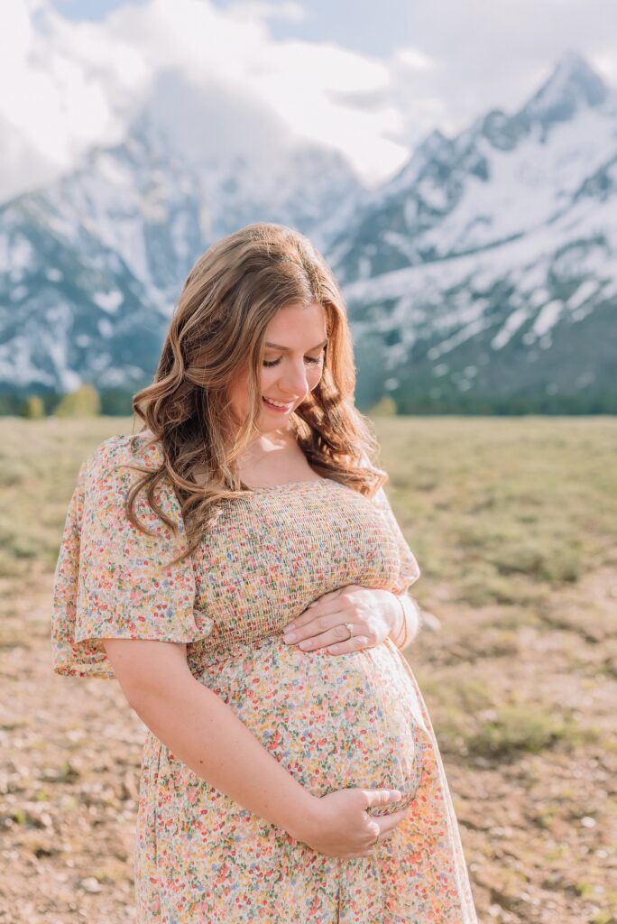 Jackson Hole babymoon maternity photos at Cathedral View Turnout Grand Teton National Park maternity session in spring Cathedral View Turnout couple photos snow capped peaks Flowery maternity dress mountain photography Jackson Hole Jackson Hole Maternity Photographer