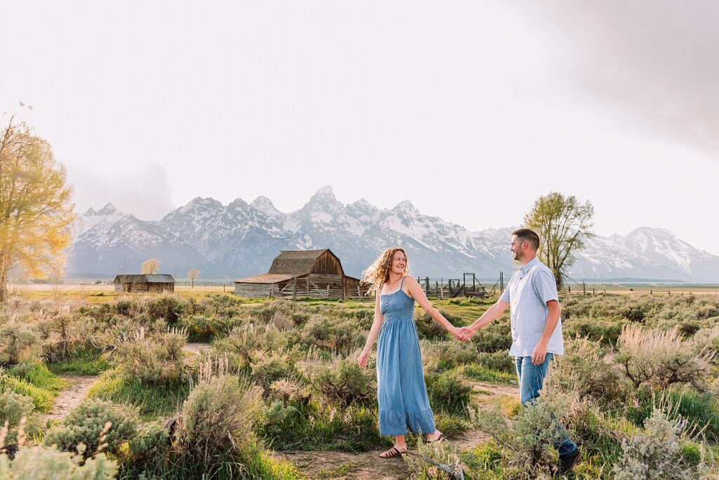 golden hour couples photography Mormon Row Jackson Hole Teton mountain backdrop engagement photos Wyoming blue coordinated outfits couples portraits Grand Tetons historic barn couples photography Jackson Hole Wyoming spring aspen trees anniversary session Mormon Row rustic fence line portraits Grand Teton National Park