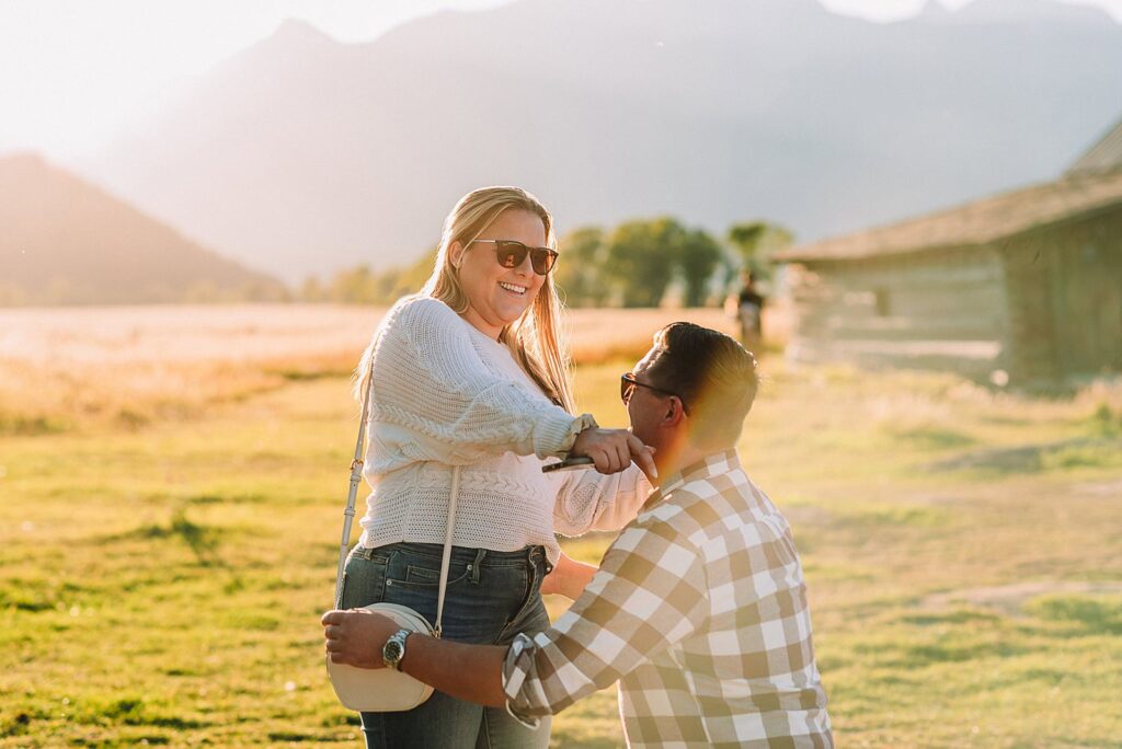 Mormon Row barn proposal photography Jackson Hole Wyoming Sunset engagement photos at TA Moulton Barn Surprise proposal photographer Grand Teton National Park Golden hour mountain proposal photography Jackson Hole Authentic couple portraits Mormon Row historic barn
