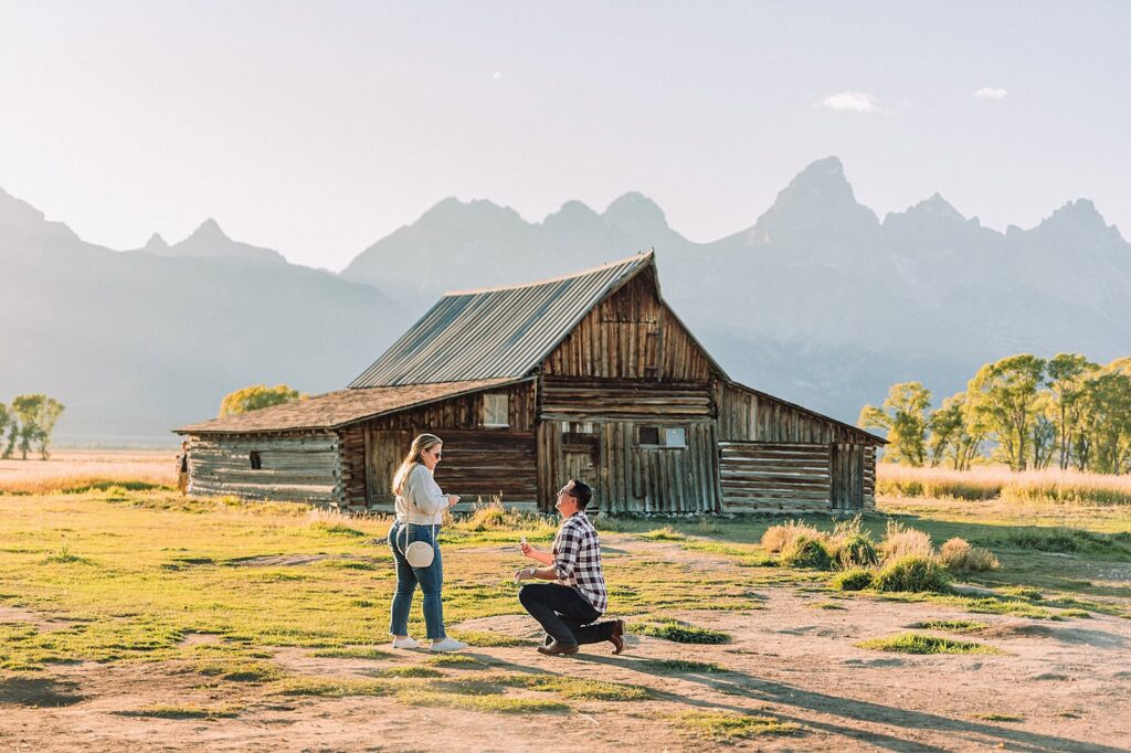 Mormon Row barn proposal photography Jackson Hole Wyoming Sunset engagement photos at TA Moulton Barn Surprise proposal photographer Grand Teton National Park Golden hour mountain proposal photography Jackson Hole Authentic couple portraits Mormon Row historic barn