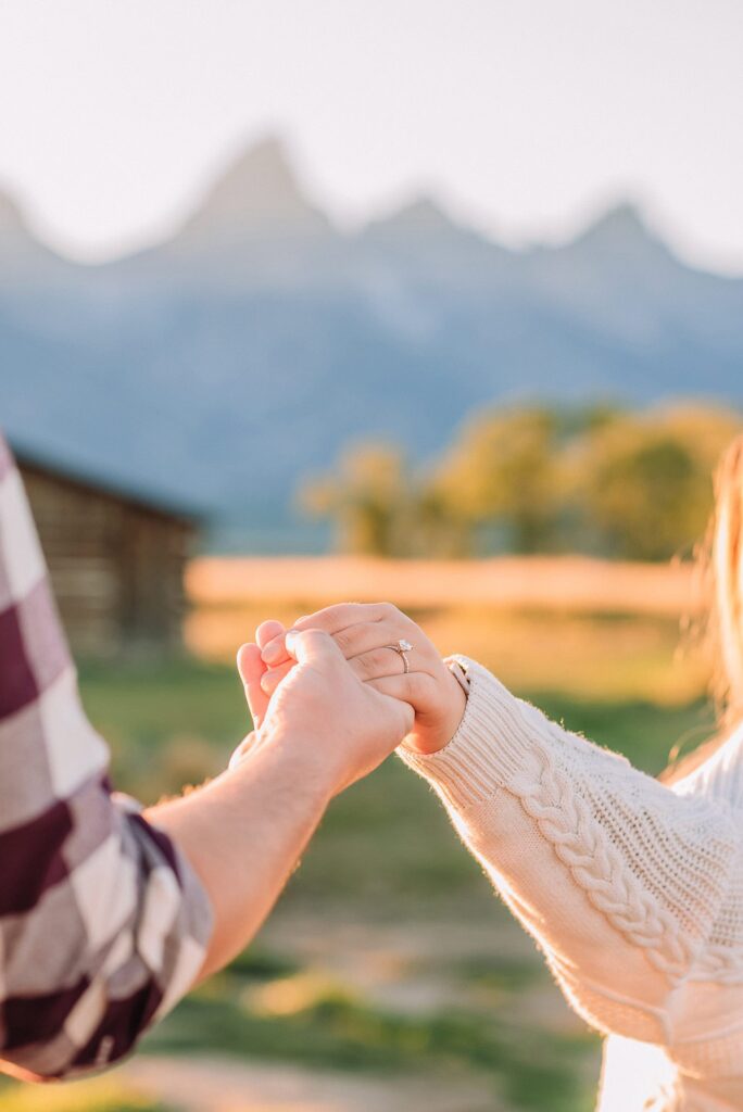 Golden hour mountain proposal photography Jackson Hole Authentic couple portraits Mormon Row historic barn Jackson Hole mountain engagement session summer sunset Candid proposal moment Teton mountain backdrop photography Romantic Wyoming barn proposal photos golden light
