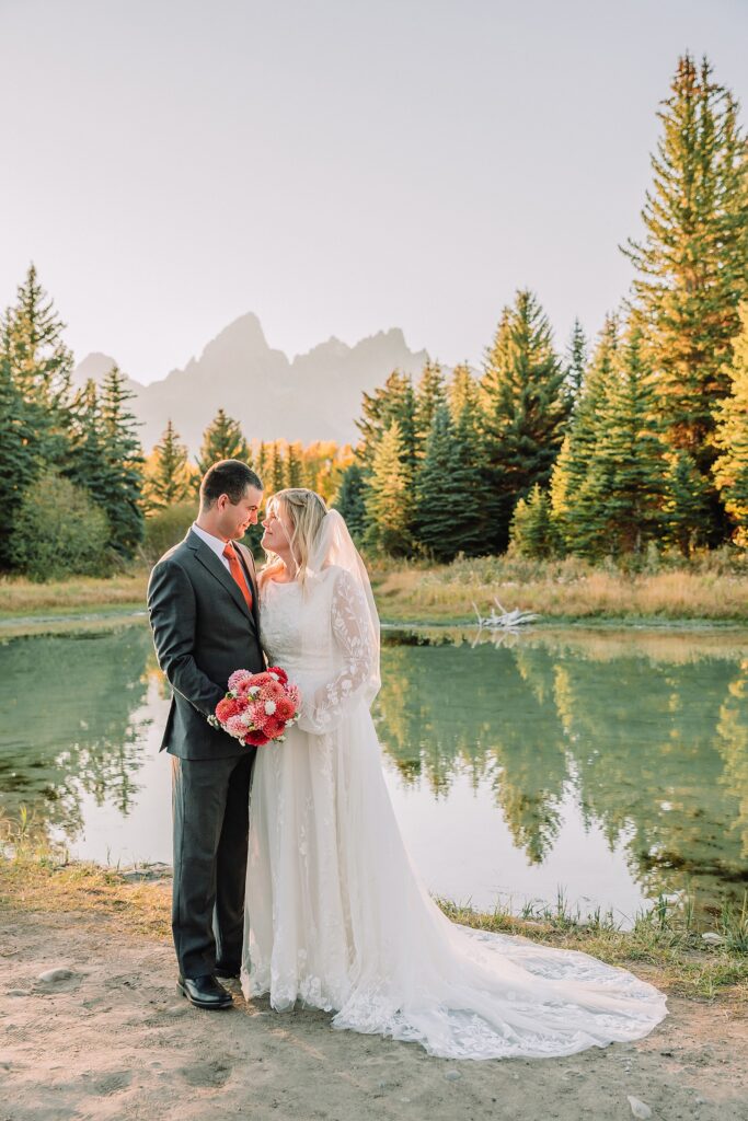 fall bridal portraits at Schwabacher Landing Jackson Hole Grand Teton National Park engagement photos String Lake bride in lace wedding dress with mountain backdrop Wyoming Schwabacher Landing fall color wedding photography Jackson Hole couple portraits with Snake River reflection bride and groom in fall foliage Grand Teton Wyoming rust orange tie groom wedding portraits Jackson Hole fall September engagement photos String Lake Teton National Park