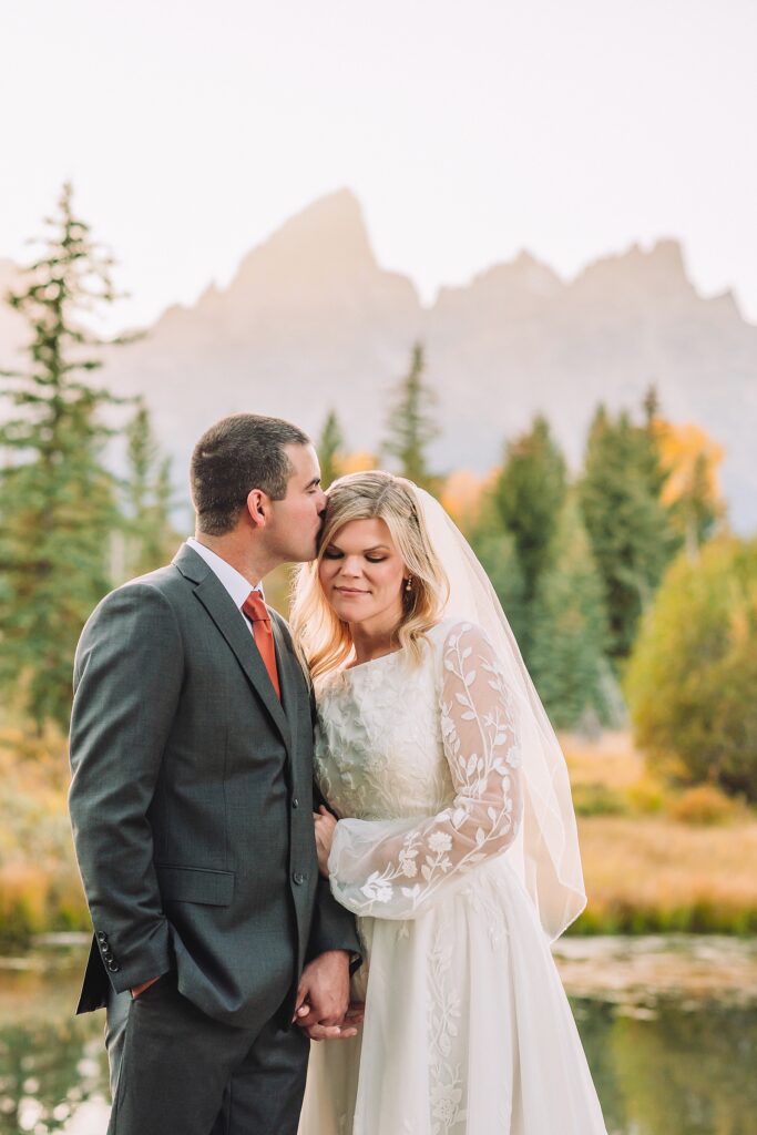 fall bridal portraits at Schwabacher Landing Jackson Hole Grand Teton National Park engagement photos String Lake bride in lace wedding dress with mountain backdrop Wyoming Schwabacher Landing fall color wedding photography Jackson Hole couple portraits with Snake River reflection bride and groom in fall foliage Grand Teton Wyoming rust orange tie groom wedding portraits Jackson Hole fall September engagement photos String Lake Teton National Park