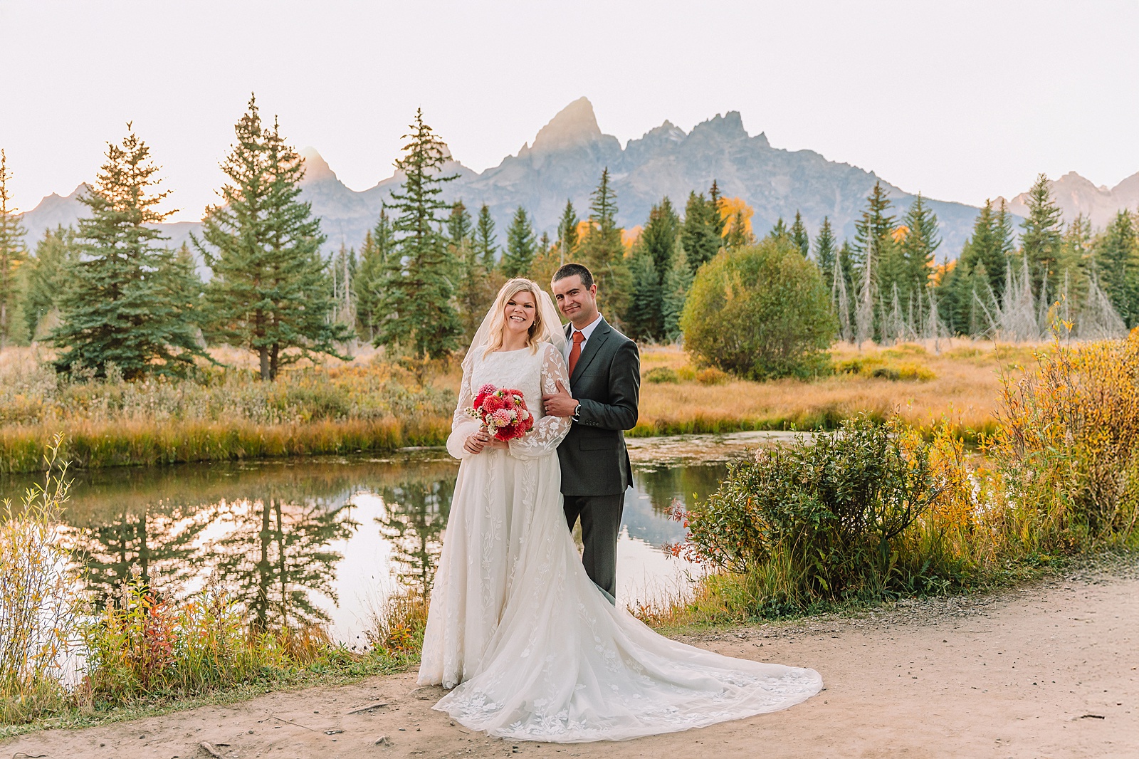 fall bridal portraits at Schwabacher Landing Jackson Hole Grand Teton National Park engagement photos String Lake bride in lace wedding dress with mountain backdrop Wyoming Schwabacher Landing fall color wedding photography Jackson Hole couple portraits with Snake River reflection bride and groom in fall foliage Grand Teton Wyoming rust orange tie groom wedding portraits Jackson Hole fall September engagement photos String Lake Teton National Park