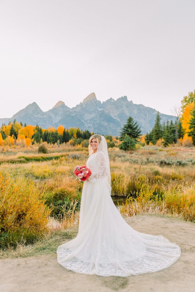 fall bridal portraits at Schwabacher Landing Jackson Hole Grand Teton National Park engagement photos String Lake bride in lace wedding dress with mountain backdrop Wyoming Schwabacher Landing fall color wedding photography Jackson Hole couple portraits with Snake River reflection bride and groom in fall foliage Grand Teton Wyoming rust orange tie groom wedding portraits Jackson Hole fall September engagement photos String Lake Teton National Park