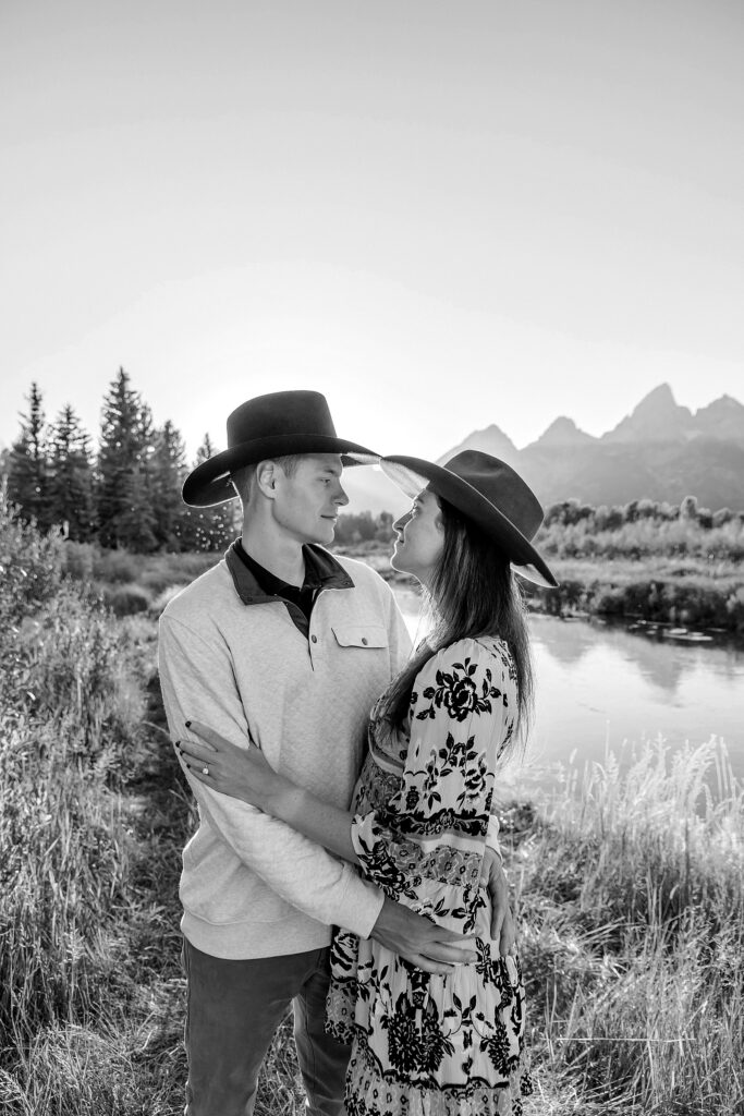 Jackson Hole engagement photos at Schwabacher Landing fall colors couple portraits along Snake River Wyoming autumn surprise engagement session Grand Teton National Park western hats engagement photos Jackson Wyoming fall engagement photos sagebrush Tetons backdrop blue dress engagement photos Jackson Hole Wyoming Schwabacher Landing couples photography fall season golden cottonwood trees engagement portraits Wyoming