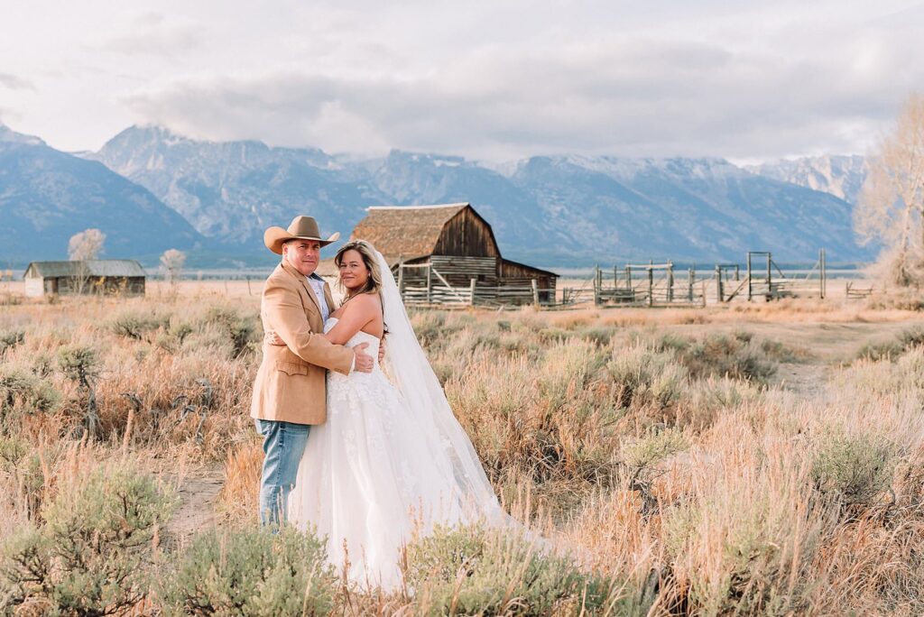 Mormon Row barn elopement photos with Grand Teton mountains fall elopement portraits at Mormon Row historic barns cowboy hat groom Mormon Row wedding photos Schwabacher Landing elopement reflection photos elopement ceremony Jackson Hole