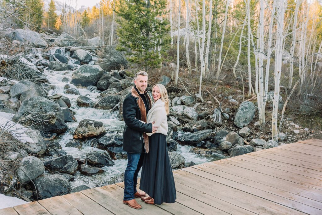 Taggart Lake engagement photography Jackson Hole Wyoming Grand Teton couples anniversary photos spring session Wyoming mountain bridge waterfall couple portraits Luxury western couples photography Jackson Hole Early season mountain engagement photos Tetons