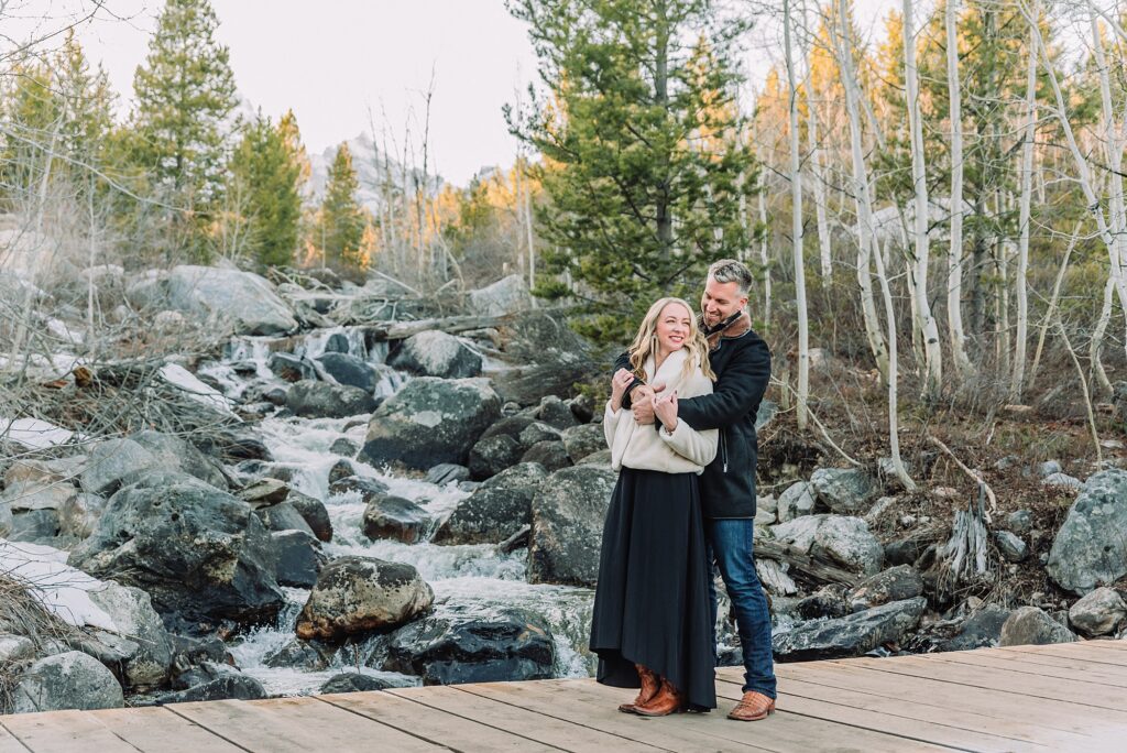 Taggart Lake engagement photography Jackson Hole Wyoming Grand Teton couples anniversary photos spring session Wyoming mountain bridge waterfall couple portraits Luxury western couples photography Jackson Hole Early season mountain engagement photos Tetons