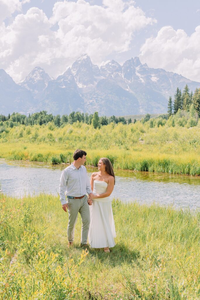 summer engagement photos at Schwabacher Landing Wyoming mountain engagement session with river views Grand Tetons white dress engagement photos in nature Teton mountain backdrop engagement photography outdoor engagement photos with cloudy blue skies