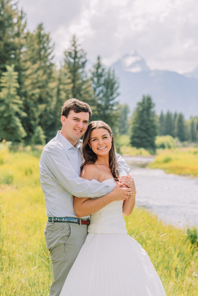 summer engagement photos at Schwabacher Landing Wyoming mountain engagement session with river views Grand Tetons white dress engagement photos in nature Teton mountain backdrop engagement photography outdoor engagement photos with cloudy blue skies