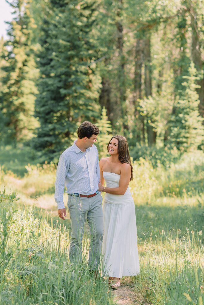 summer engagement photos at Schwabacher Landing Wyoming mountain engagement session with river views Grand Tetons white dress engagement photos in nature shaded forest engagement photos summer session outdoor engagement photos with cloudy blue skies