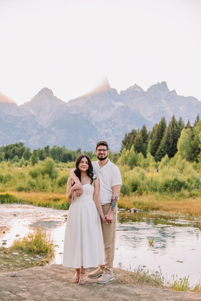 Schwabacher Landing engagement photos Grand Teton National Park white corset dress mountain engagement session Wyoming sunset engagement photos Teton mountain range backdrop couple wearing white outfits Grand Teton engagement shoot Jackson Hole Engagement Photographer