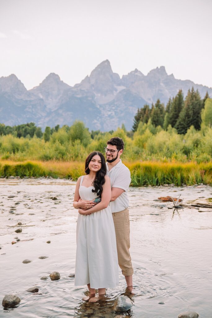 Schwabacher Landing engagement photos Grand Teton National Park white corset dress mountain engagement session Wyoming sunset engagement photos Teton mountain range backdrop couple wearing white outfits Grand Teton engagement shoot Jackson Hole Engagement Photographer